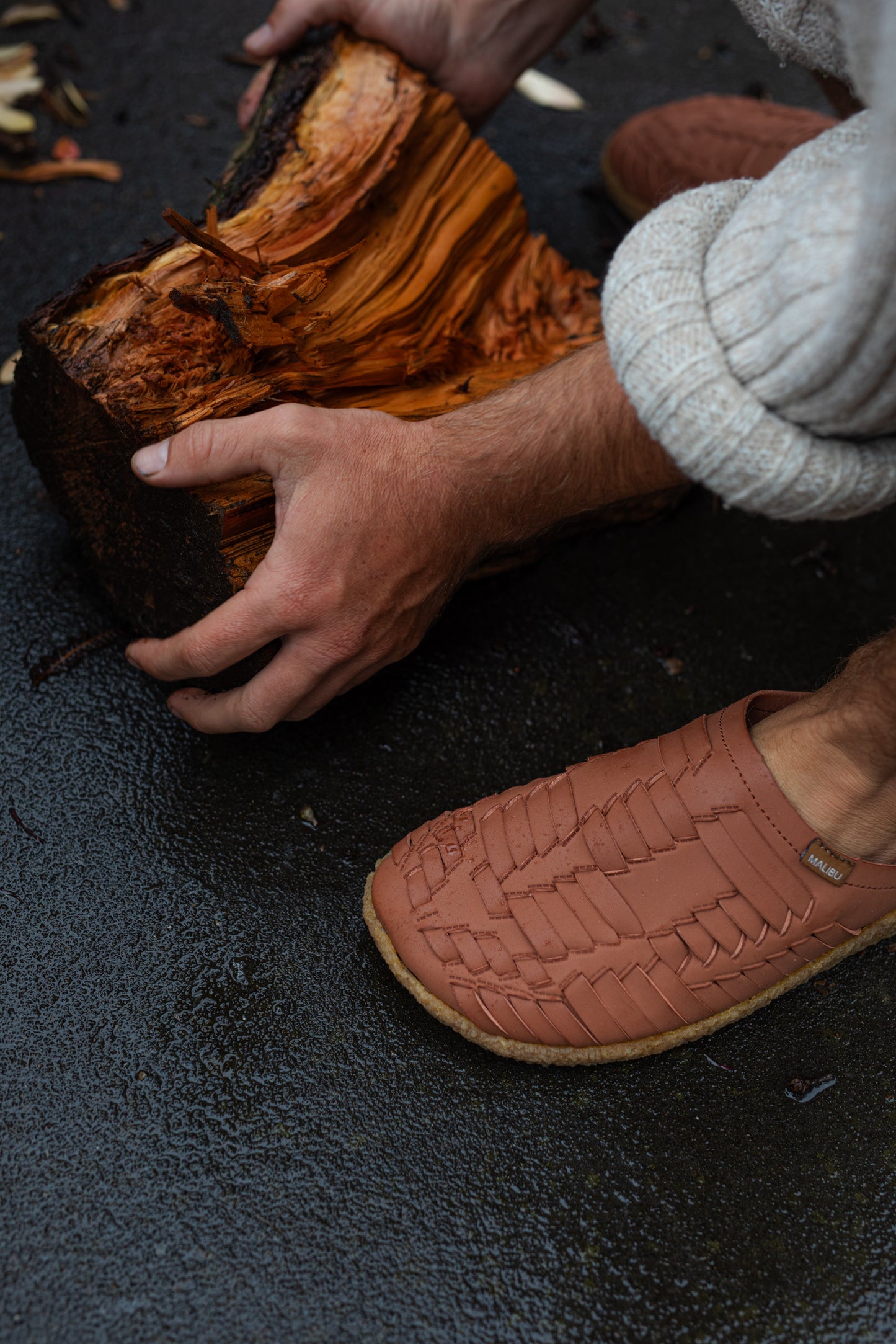 close up photo of Malibu Sandals Thunderbird clog with the person about to pick up a piece of wood with hands w
