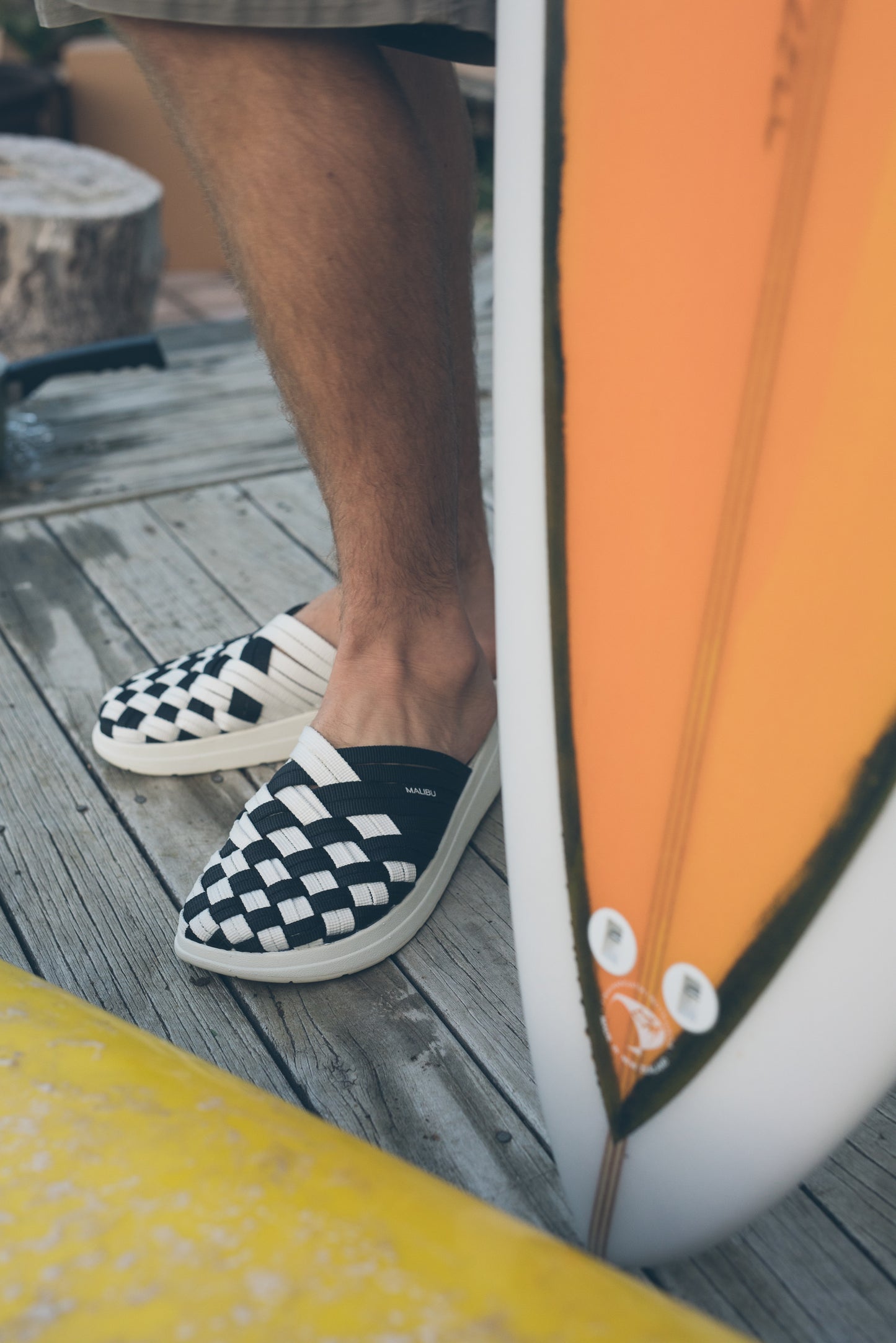 Black and White Nylon Colony sandal with Eva rubber Sole next to a surfboard