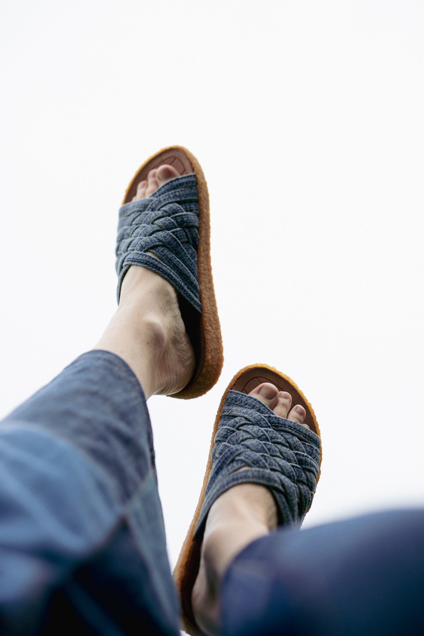 Portrait shot of feet in the sky wearing orSlow x Malibu Sandals Washed Indigo Zuma Sandal with crepe sole 